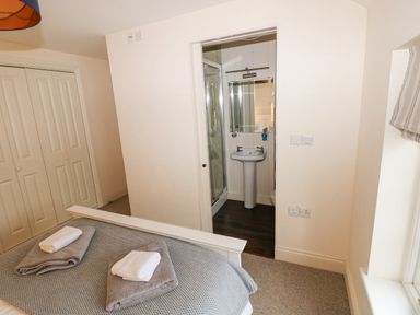 A bedroom with a bed and towels on it next to a bathroom with a sink and shower at The Old Boathouse in Trefin near St Davids