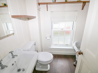 A bathroom with a sink, toilet, window, and clawfoot bathtub at The Old Boathouse in Trefin near St Davids