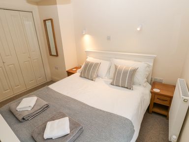 A bedroom with a double bed two bedside tables a wall mirror and a radiator at The Old Boathouse in Trefin near St Davids