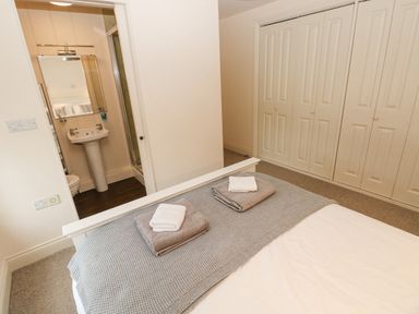A bedroom with a bed and towels on it and an ensuite bathroom with a sink and mirror at The Old Boathouse in Trefin near St Davids