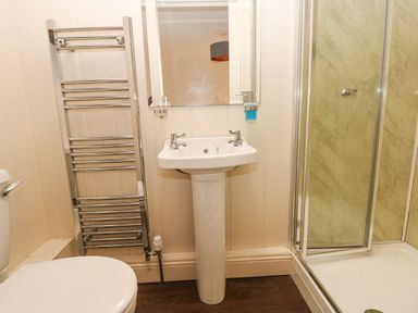 A bathroom with a toilet sink towel rack and shower at The Old Boathouse in Trefin near St Davids