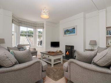 A living room with grey sofas a coffee table a fireplace and a television at 21 Passage Street formerly Panacea in Fowey