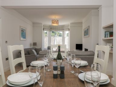 A dining table set with plates glasses and cutlery in a living room with sofas and a window at 21 Passage Street formerly Panacea in Fowey