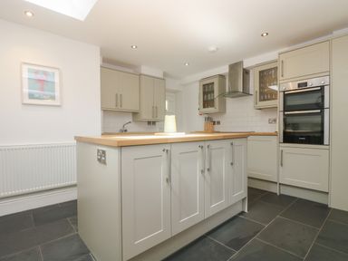 A kitchen with cabinets island unit double oven and tiled floor at 21 Passage Street formerly Panacea in Fowey