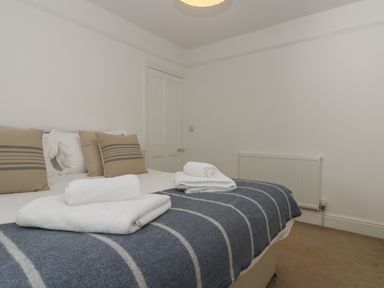 A bedroom with a bed folded towels and striped pillows at 21 Passage Street formerly Panacea in Fowey