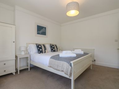 A bedroom with a double bed and pillows towels on the bed a wardrobe and bedside table with lamps at 21 Passage Street formerly Panacea in Fowey