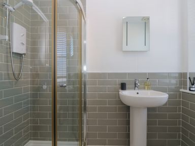 A bathroom with a shower enclosure and a pedestal sink at 21 Passage Street formerly Panacea in Fowey