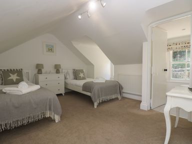 A bedroom with two single beds bedside table lamps and an open door showing a bathroom at 21 Passage Street formerly Panacea in Fowey
