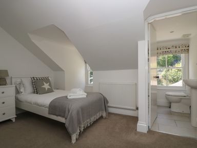 A bedroom with a single bed, bedside table with lamp, window, and an en suite bathroom with toilet and sink at 21 Passage Street formerly Panacea in Fowey