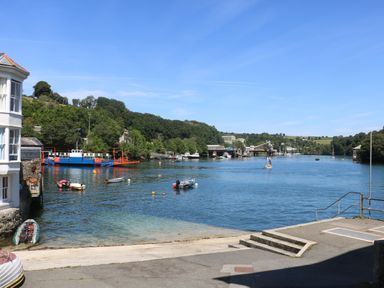 A riverside view with boats and a ferry near buildings and trees at 21 Passage Street formerly Panacea in Fowey
