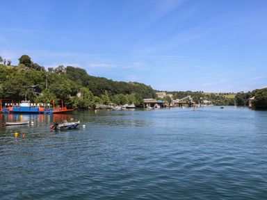 A river with boats docked near a wooded shore at 21 Passage Street formerly Panacea in Fowey