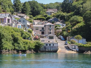A riverside view of houses cars and a person rowing a boat at 21 Passage Street formerly Panacea in Fowey