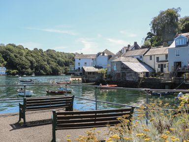 A waterfront area with benches boats on water and houses along the shore at 21 Passage Street formerly Panacea in Fowey