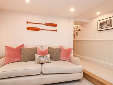 A sofa with cushions and two wooden paddles mounted on the wall above at Pilchard Cottage in Dawlish