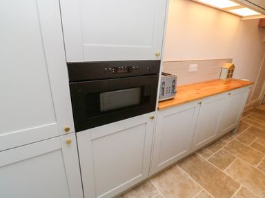 A kitchen counter with a toaster a small house decoration and built-in oven at Pilchard Cottage in Dawlish