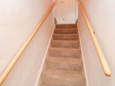 A carpeted staircase with wooden handrails on both sides at Pilchard Cottage in Dawlish