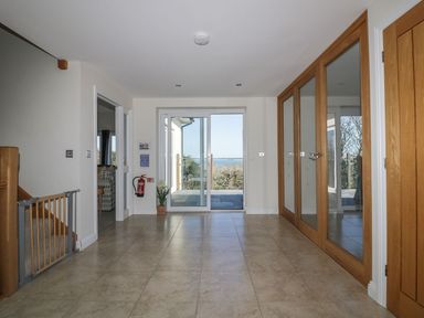 An entrance hall with tiled floor sliding glass doors and wooden framed mirrored closet doors at Lower Mellan Barn in Coverack