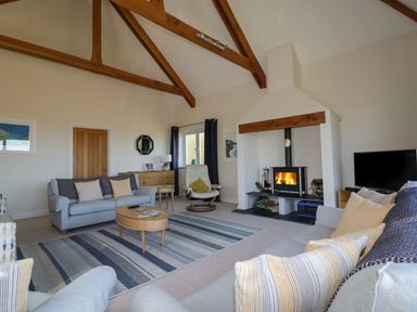 A living room with sofas coffee table fireplace and wooden ceiling beams at Lower Mellan Barn in Coverack