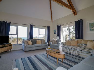 A living room with three sofas a wooden coffee table and large windows at Lower Mellan Barn in Coverack