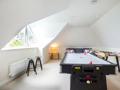 A game room with an air hockey table foosball table stools and a sofa at Lower Mellan Barn in Coverack