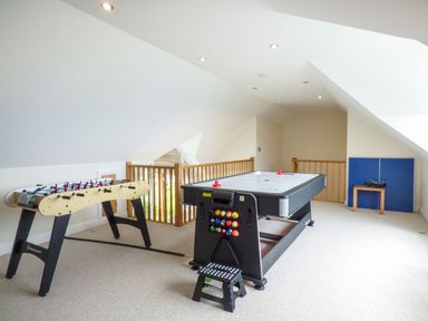 A game room with a foosball table air hockey table and a folded ping pong table at Lower Mellan Barn in Coverack