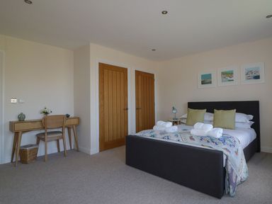 A bedroom with a bed and towels on it and a wooden desk with a chair at Lower Mellan Barn in Coverack