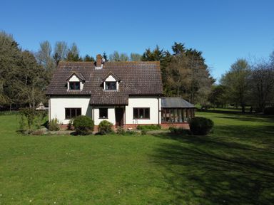 A detached house with a tiled roof and conservatory in a large garden with trees at Rivendell in Weybread near Harleston