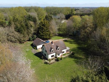 A detached house with a garage and a car on a grassy plot surrounded by trees at Rivendell in Weybread near Harleston