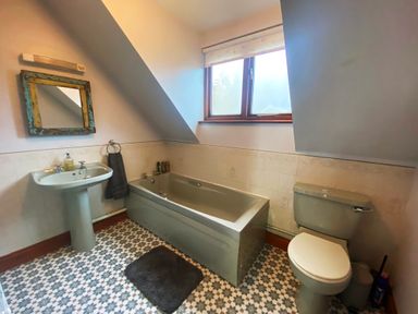 A bathroom with a bathtub sink toilet mirror and window at Rivendell in Weybread near Harleston