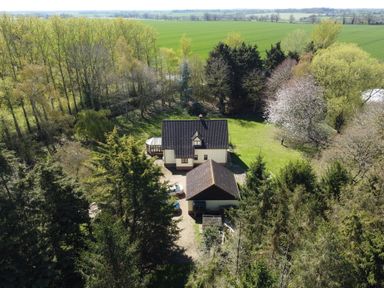 An aerial view of a house surrounded by trees and greenery with a driveway and outbuilding at Rivendell Weybread near Harleston