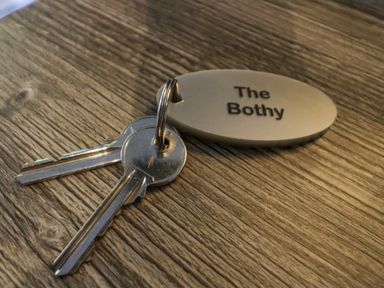 A set of two metal keys with a keyring attached to an oval tag labeled The Bothy on a wooden surface at The Bothy in Keswick