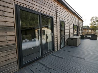 A wooden deck with sliding glass doors and outdoor seating at The Bothy in Keswick