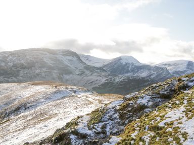 A snow-covered mountain landscape with a trail and distant peaks