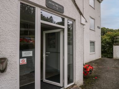 An entrance door to apartments 1 to 6 with a potted plant with red flowers outside at Apartment 1 in Keswick