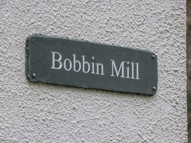 A wall-mounted sign with the text Bobbin Mill on a textured wall at Apartment 1 in Keswick