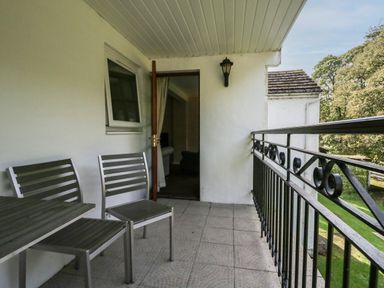 A balcony with two metal chairs a table and a black metal railing at Apartment 1 in Keswick