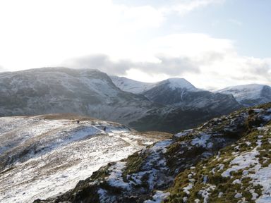 A snow-dusted mountain landscape with a pathway and distant hills under a partly cloudy sky at Apartment 1 Keswick