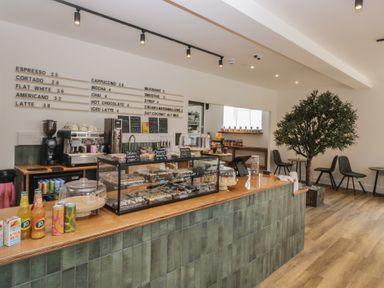 A cafe counter with a coffee machine and display case at Apartment 1 in Keswick