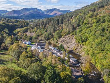 An aerial view of a village near a river with mountains in the background at Apartment 1 Keswick
