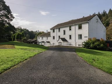 A driveway leading to a white multi-story building surrounded by grass and trees at Apartment 2 in Keswick