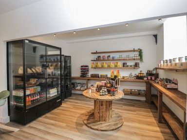 A grocery store with a wooden table and shelves filled with various food items at Apartment 2 in Keswick