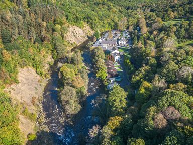 An aerial view of houses alongside a river and trees in Keswick