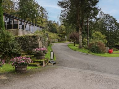 A driveway leading to a house with flower pots near stone steps and trees along the road at Apartment 3 in Keswick
