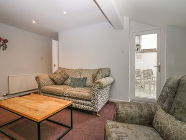 A sitting room with patterned sofas and a wooden coffee table near a glass door leading outside at Apartment 6 in Keswick