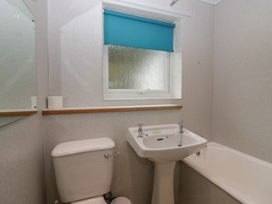 A bathroom with a toilet sink bathtub and a blue window blind at Apartment 6 Keswick