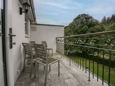A balcony with four chairs and a metal railing overlooking trees at Apartment 6 in Keswick
