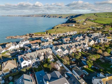 A coastal village with houses near the sea and green fields at Tre Lowen in Port Isaac