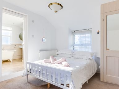 A bedroom with a white bed and rolled towels next to a bathroom with a bathtub at Tre Lowen in Port Isaac