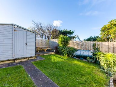 A garden with a shed a picnic table plants and a fenced boundary at Tre Lowen in Port Isaac