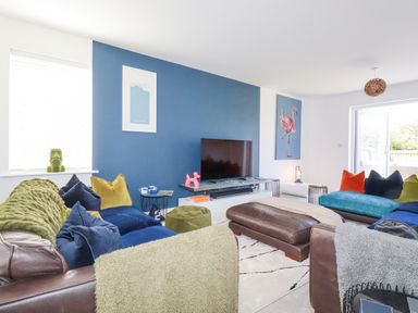A living room with sofas and a television on a blue accent wall at Cobalt in St Eval near Mawgan Porth